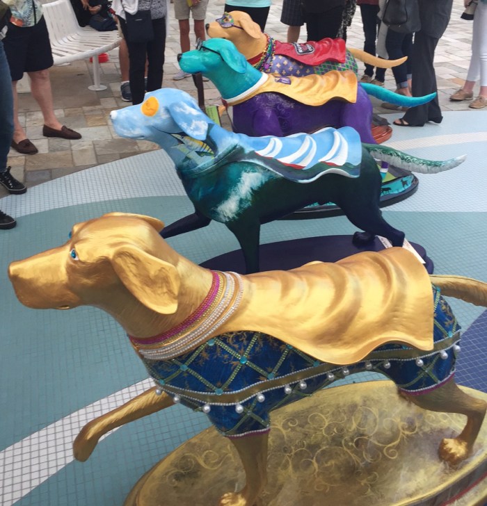 Four caped, colorfully painted superdog statues